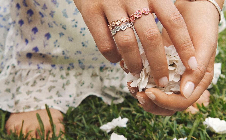 Model picking daisies, wearing Pandora Garden daisy rings, bracelet and charms.