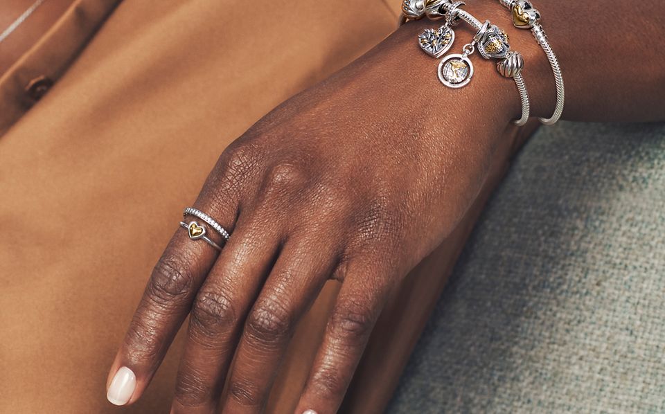 Modelka nosząca dwutonowe pierścionki bransoletki i charmsy Pandora Moments.