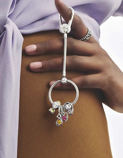Model holding a sterling silver bag carrier with charms from Disney x Pandora