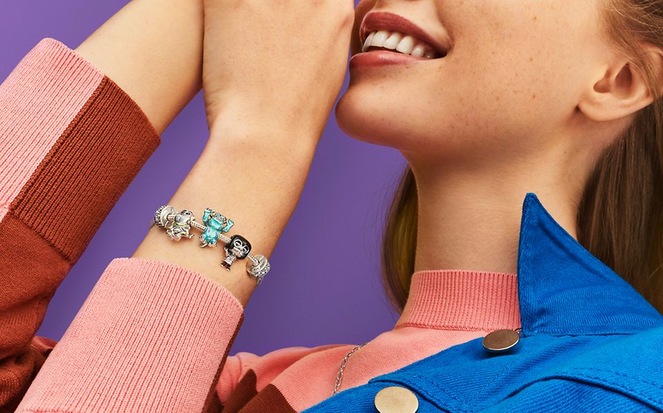 Woman wears a silver bracelet with Charms from the Pixar collection
