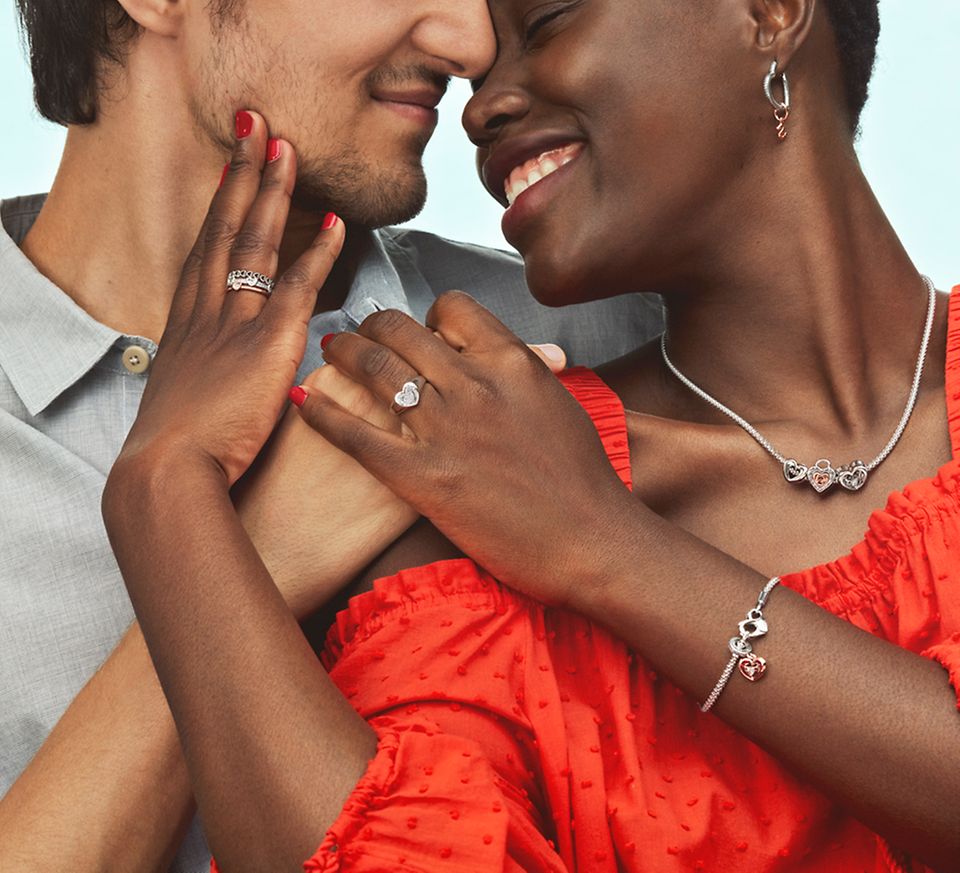 Lächelnde Frauen mit Armband, Halskette und Ohrringen umarmen einen Mann
