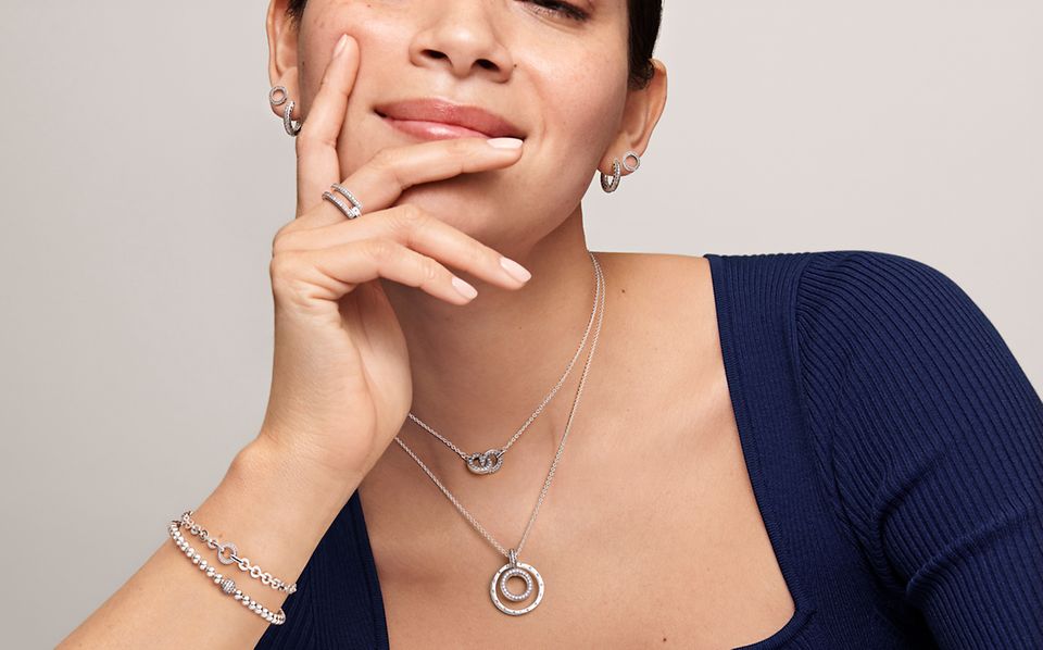 Kvinde, der bærer Pandora Signature stabelbare ringe, armbånd, øreringe og halskæder