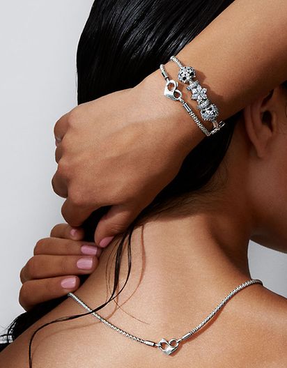 Mujer con un collar de cadena con tachuelas y combinación de dos pulseras de distintos metales