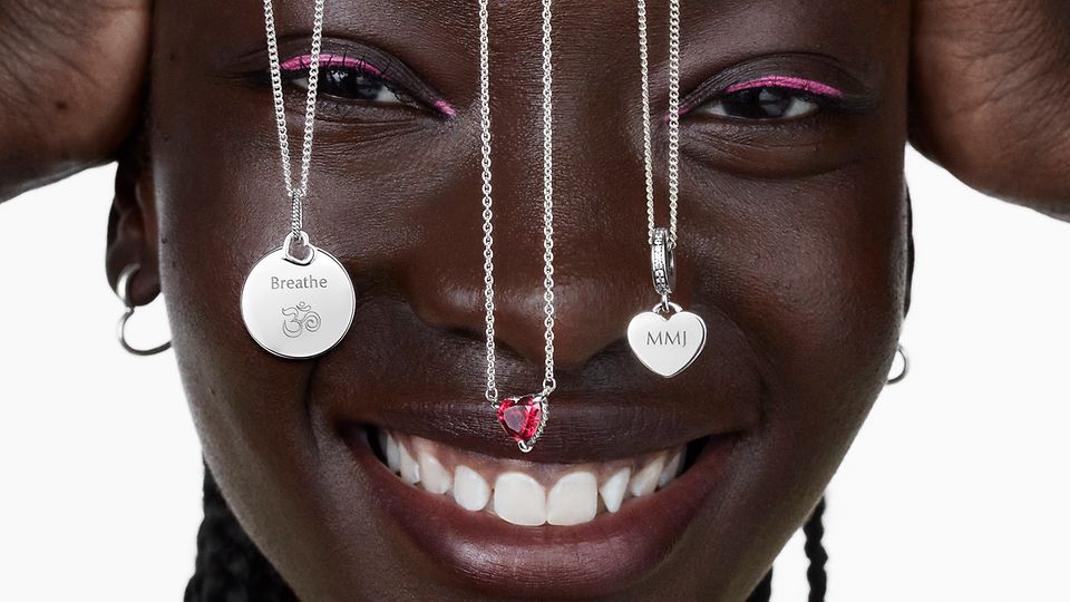 Mujer sonriendo con tres collares en plata de primera ley de Pandora colgando sobre su rostro