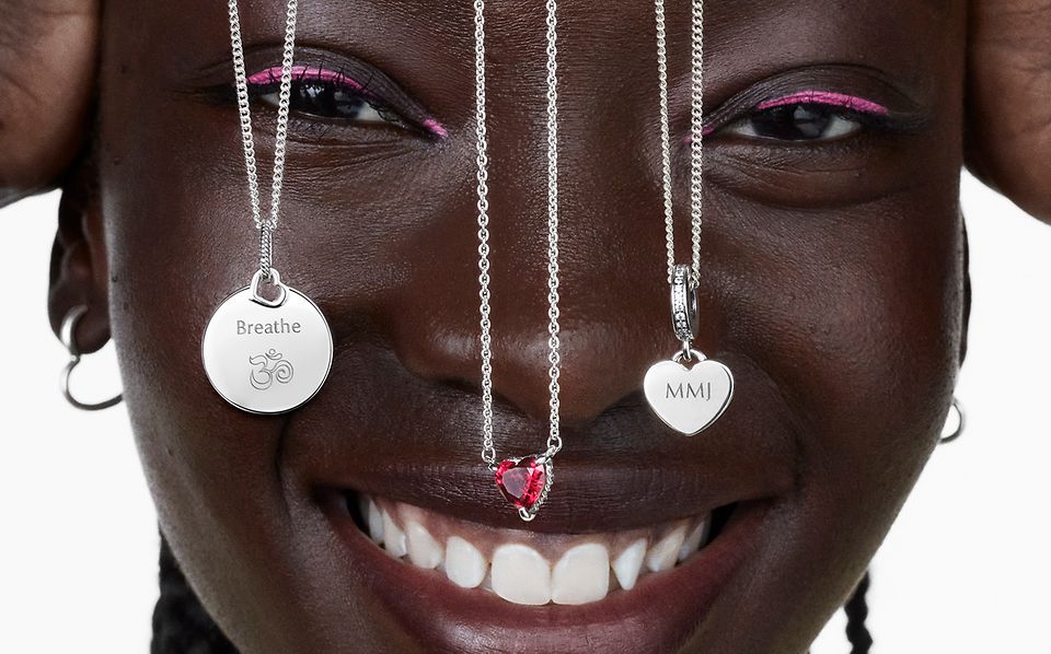 Femme souriante avec trois colliers Pandora en argent devant son visage