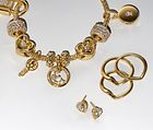 Bild av Pandora BE LOVE guldarmband med berlock som pryds av en artificiell diamant och fem örhängen.