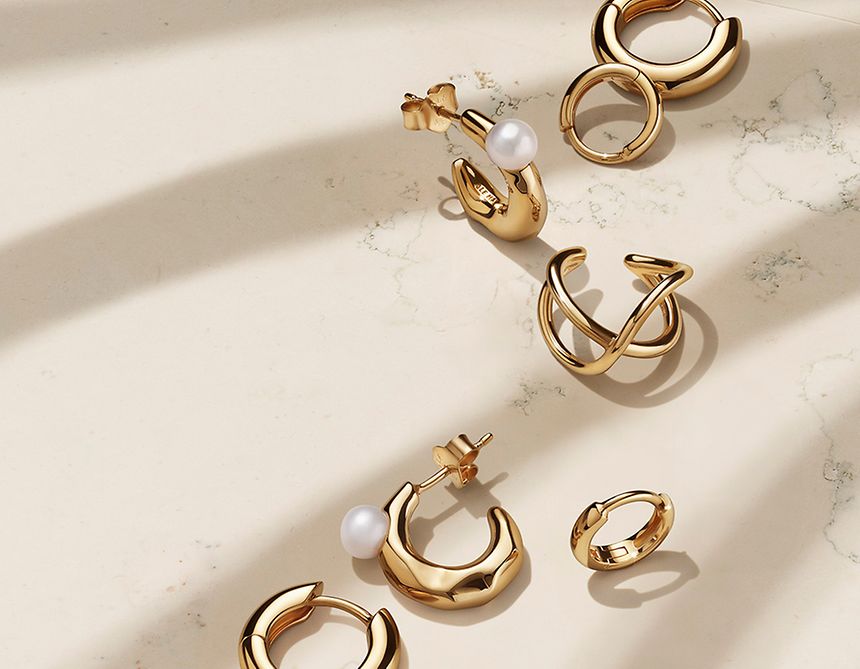 Złote kolczyki obręcze Pandora Essence z perłami.