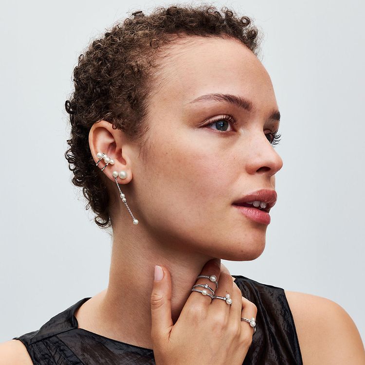 Model wears pearls silver drop earrings and stacking rings.