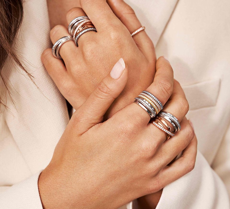 A model's hands wearing Pandora stackable rings in silver and Pandora Rose™